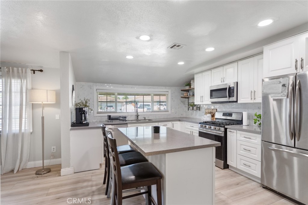 1005 North Encina Avenue Rialto, CA 92376 - Photo 11 of 39 a kitchen with stainless steel appliances granite countertop a refrigerator a sink dishwasher a stove and white countertops with wooden floor