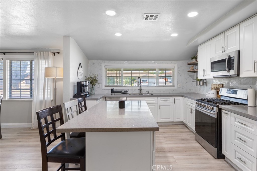 1005 North Encina Avenue Rialto, CA 92376 - Photo 10 of 39 a kitchen with stainless steel appliances granite countertop a stove a sink a microwave a dining table and chairs