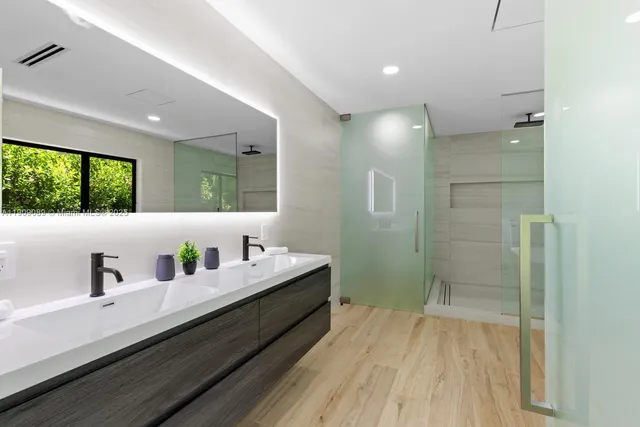 a bathroom with a double vanity sink a mirror and a shower