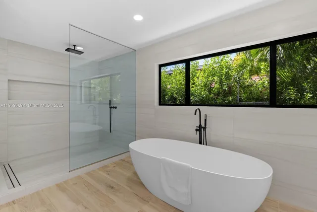 a white bath tub sitting in a bathroom next to a window