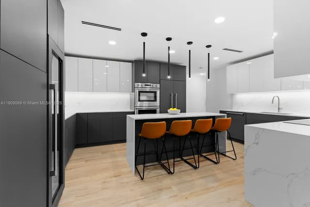 a kitchen with stainless steel appliances kitchen island granite countertop a table chairs in it and wooden floors