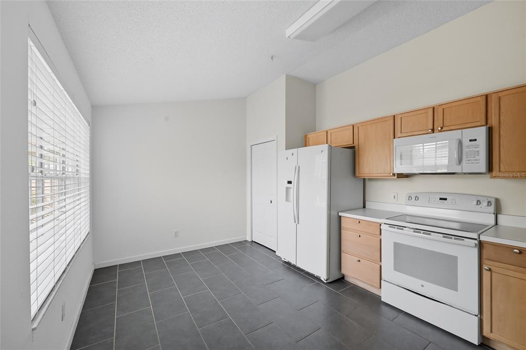 6029 Lake Pointe Drive, Unit 202 Orlando, FL 32822 - Photo 9 of 28 a kitchen with white cabinets and white appliances