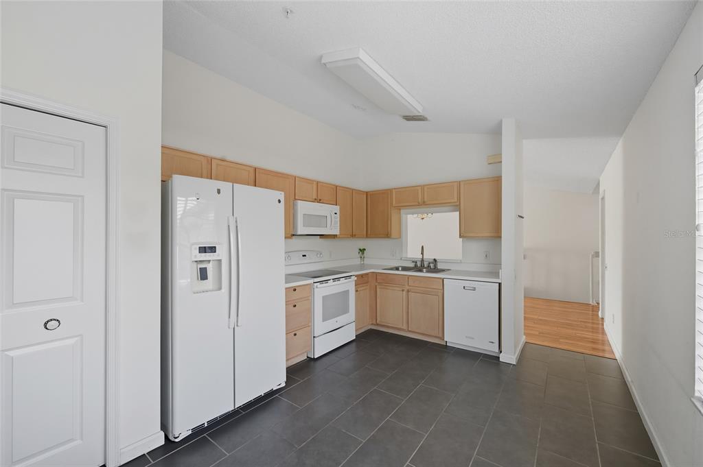 6029 Lake Pointe Drive, Unit 202 Orlando, FL 32822 - Photo 10 of 28 a kitchen with white cabinets and white appliances