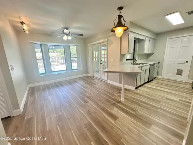 a room with kitchen island stainless steel appliances wooden floor and window