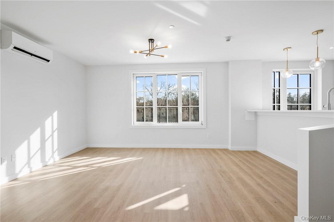 139 Fifth Avenue, Unit 5C Pelham, NY 10803 - Photo 7 of 32 an empty room with wooden floor chandelier and windows