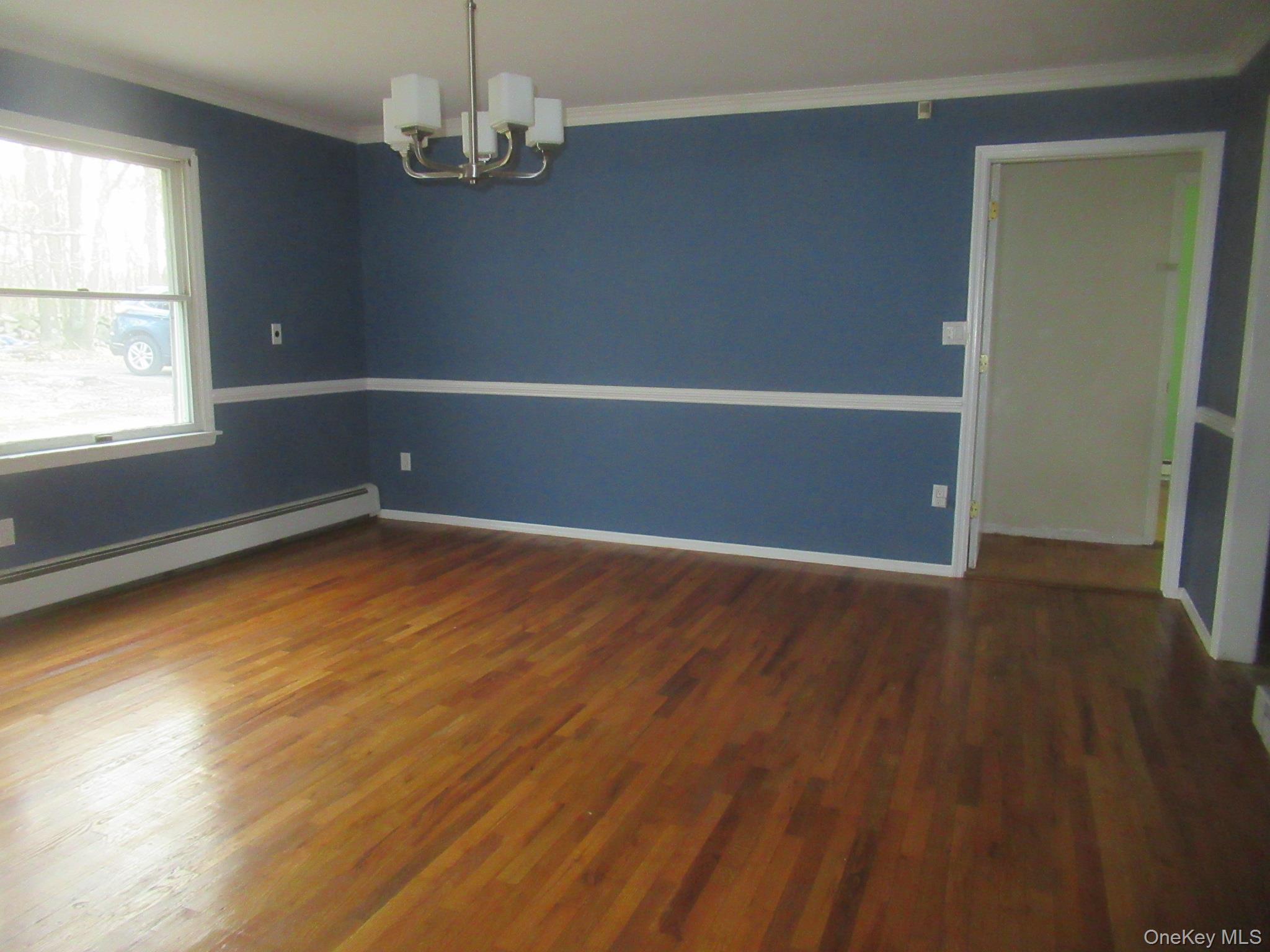 64 Hillside View Road Mahopac, NY 10541 - Photo 7 of 25 Unfurnished room with ornamental molding, a chandelier, and dark wood-style flooring