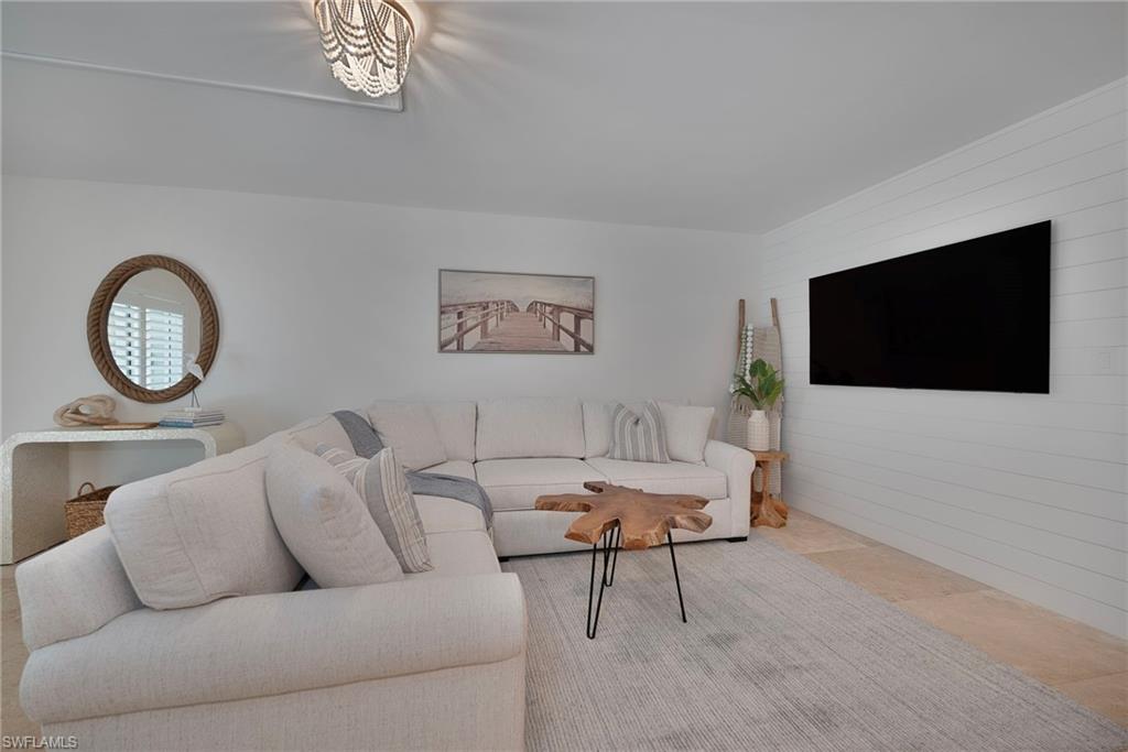 1950 Gulf Shore Boulevard North, Unit 108 Naples, FL 34102 - Photo 2 of 19 a living room with furniture and a flat screen tv
