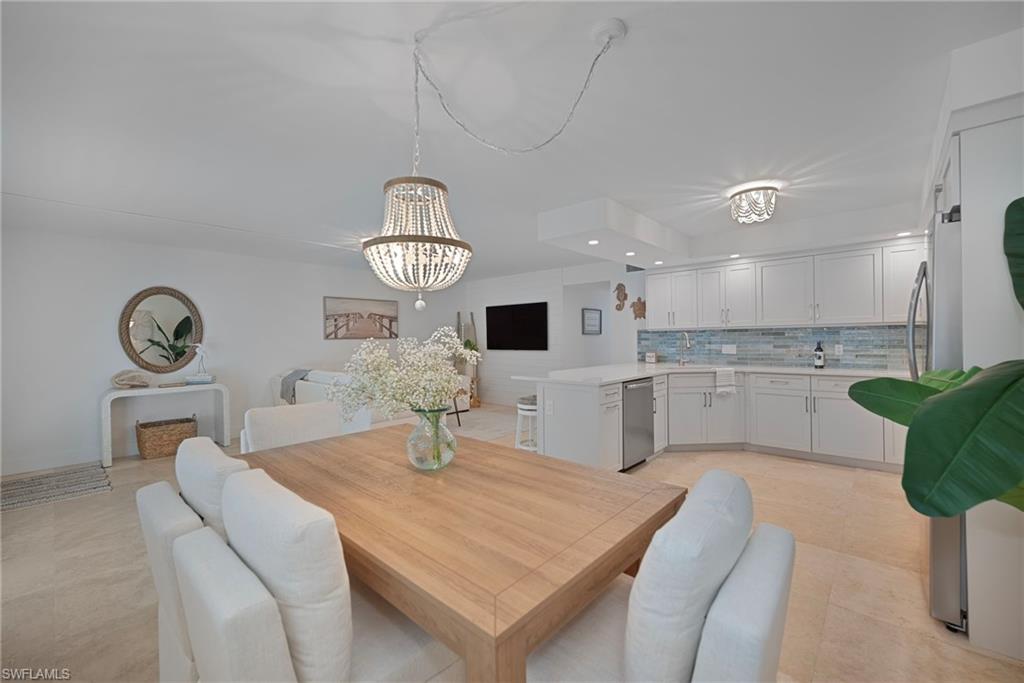 1950 Gulf Shore Boulevard North, Unit 108 Naples, FL 34102 - Photo 4 of 19 a kitchen with a table chairs and a refrigerator
