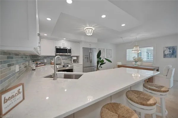 a kitchen with stainless steel appliances granite countertop a sink a stove a dining table and chairs