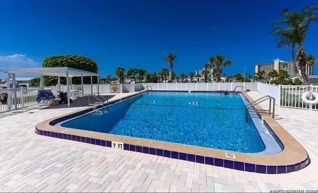 a swimming pool with lawn chairs under an umbrella