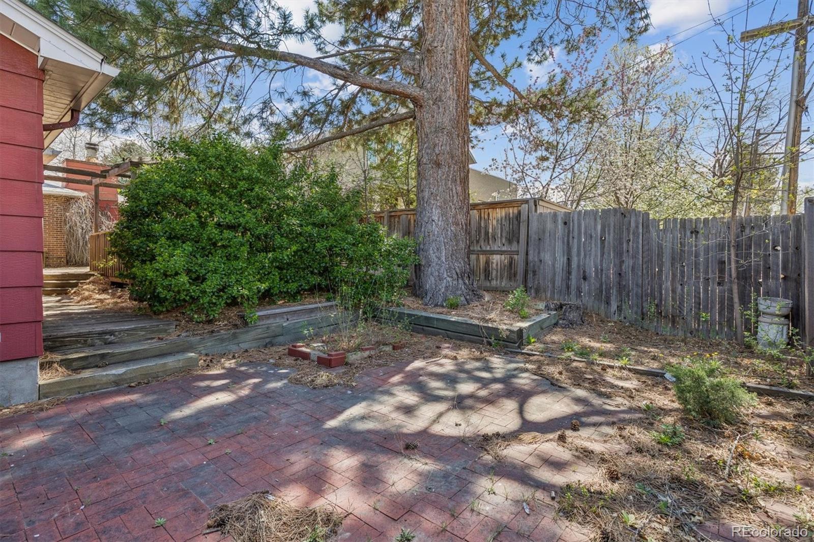 815 Oneida Street Denver, CO 80220 - Photo 34 of 39 a view of a backyard with large trees and wooden fence