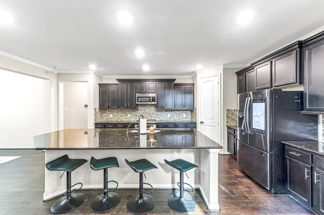 a kitchen with stainless steel appliances granite countertop a refrigerator and a stove top oven