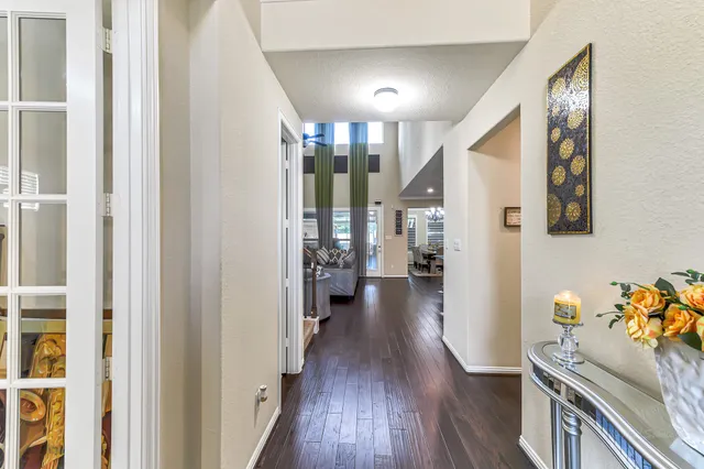a view of a hallway to a livingroom with wooden floor and windows