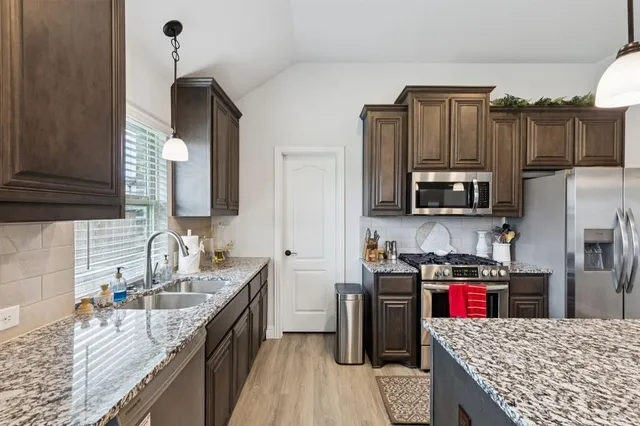 a kitchen with kitchen island granite countertop a sink counter space appliances and cabinets