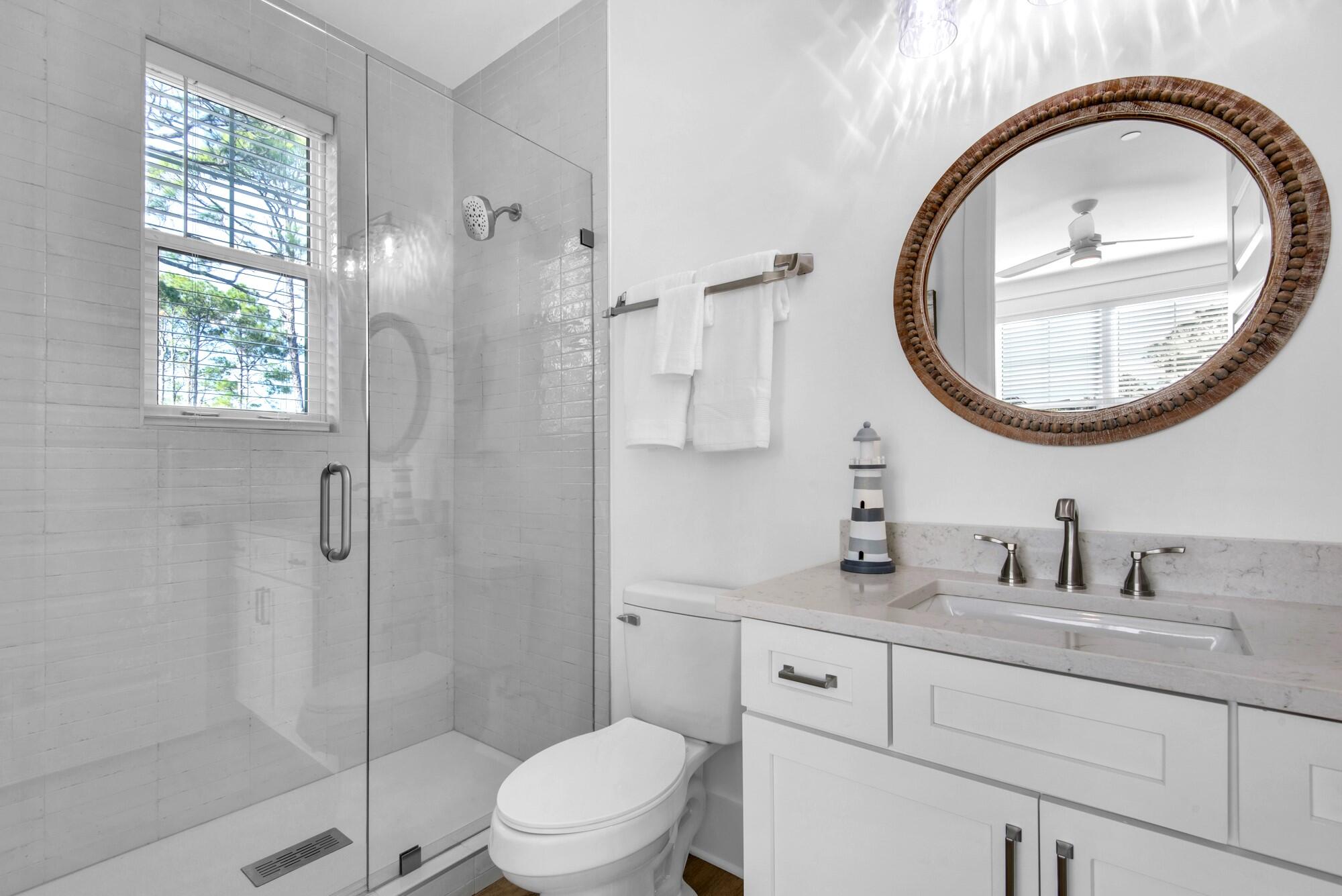 6528 West County Highway 30A Santa Rosa Beach, FL 32459 - Photo 27 of 87 a bathroom with a toilet a sink a mirror and a shower