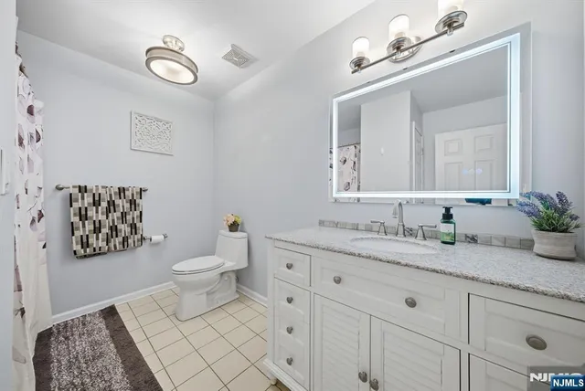 a bathroom with a granite countertop sink mirror and toilet
