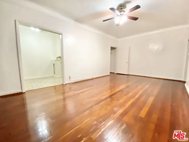 an empty room with wooden floor and a ceiling fan