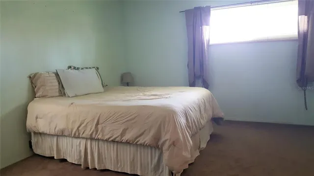a large bed sitting in a bedroom next to a window
