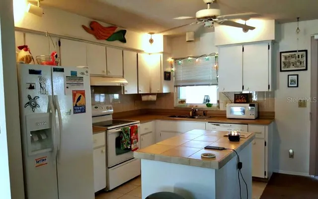 a kitchen with stainless steel appliances granite countertop a refrigerator a stove and a sink