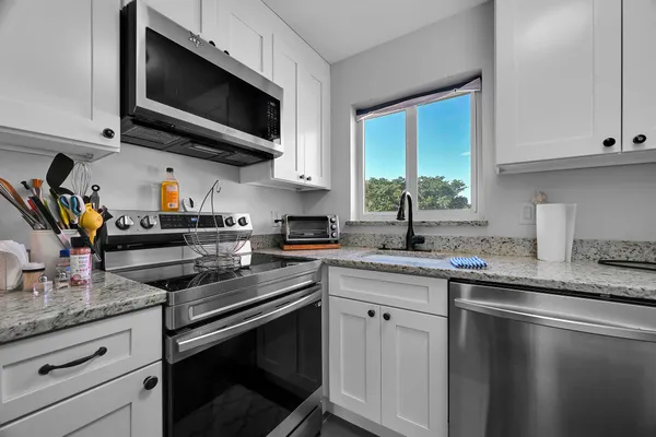 a kitchen with stainless steel appliances granite countertop a sink a stove a microwave and wooden cabinets