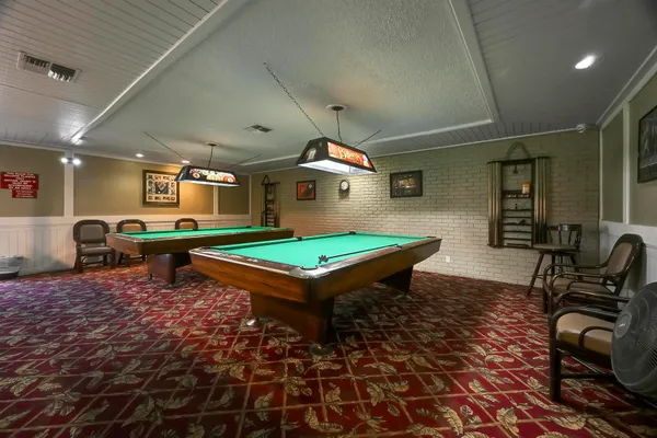 a room with chairs pool table and rug