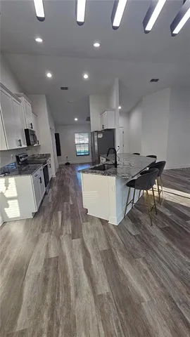 a living room with stainless steel appliances furniture a kitchen view and a couch