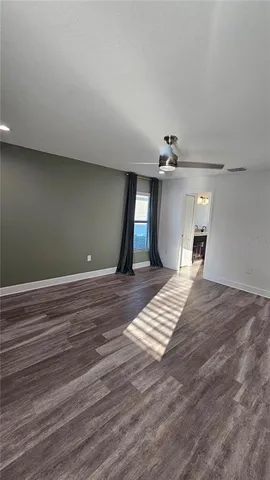 a view of an empty room with wooden floor and a window