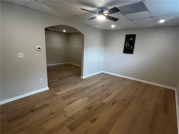 an empty room with wooden floor and a ceiling fan