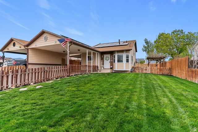 4576 South 3850 West Roy, UT 84067 - Photo 1 of 1 Rear view of house featuring roof mounted solar panels, a carport, and a patio area