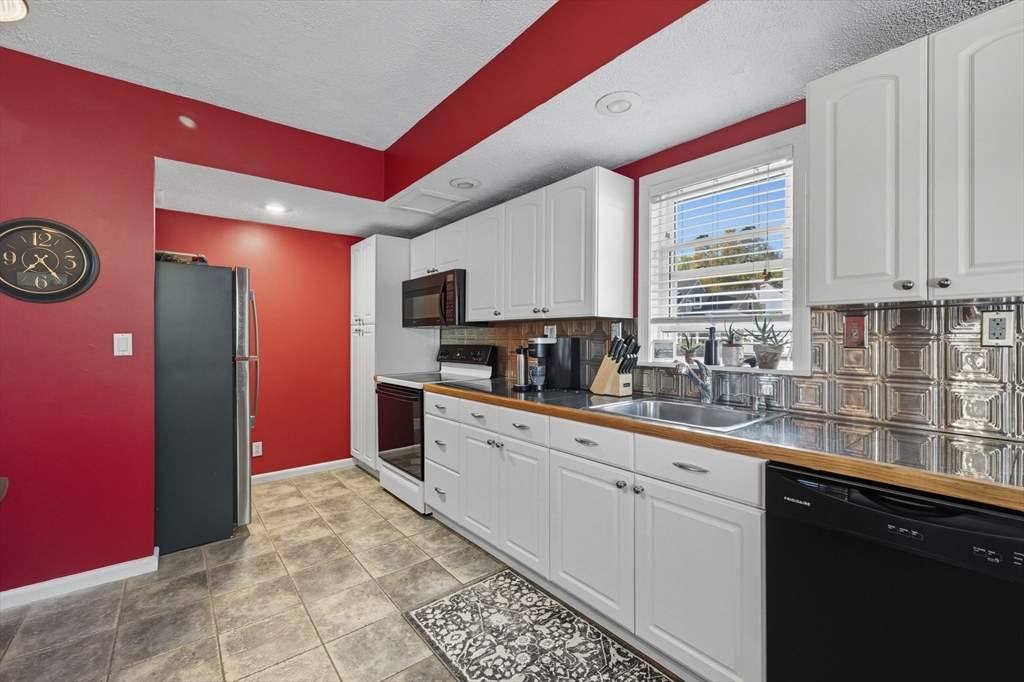 28 R School Street Danvers, MA 01923 - Photo 19 of 31 a kitchen with stainless steel appliances granite countertop a stove a sink and a microwave