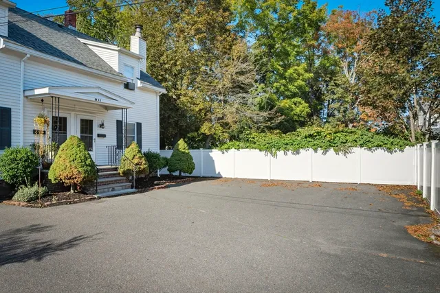 front view of a house with potted plants and a large tree