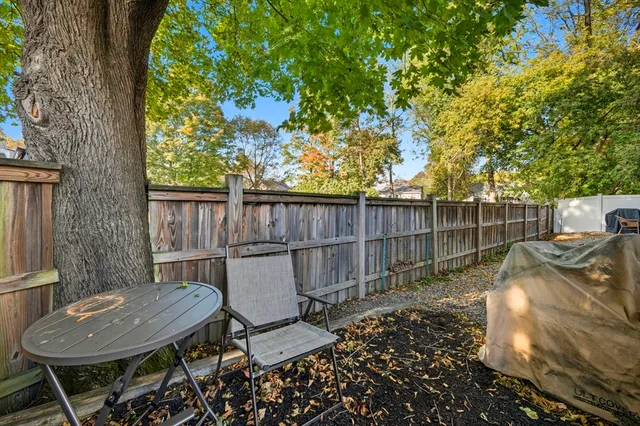 a view of a backyard with table and chairs potted plants and wooden fence