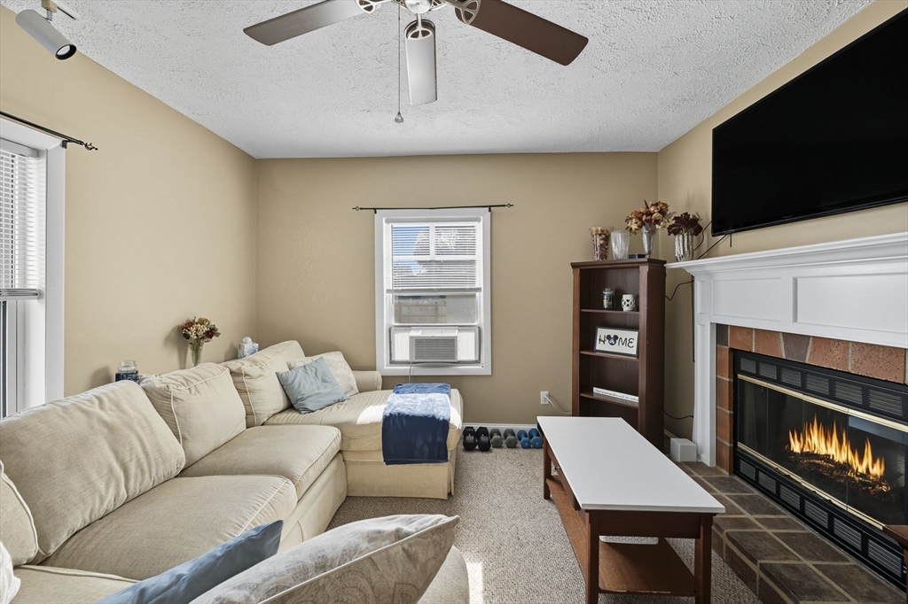 28 R School Street Danvers, MA 01923 - Photo 6 of 31 a living room with furniture a flat screen tv and a fireplace