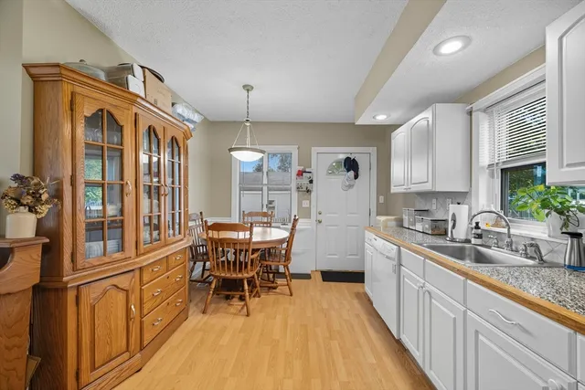 a kitchen with stainless steel appliances granite countertop a sink a stove a refrigerator cabinets and living room view