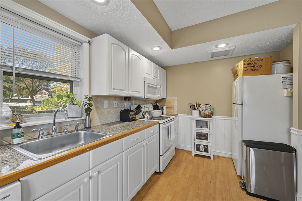 28 R School Street Danvers, MA 01923 - Photo 10 of 31 a kitchen with a refrigerator a sink and white cabinets