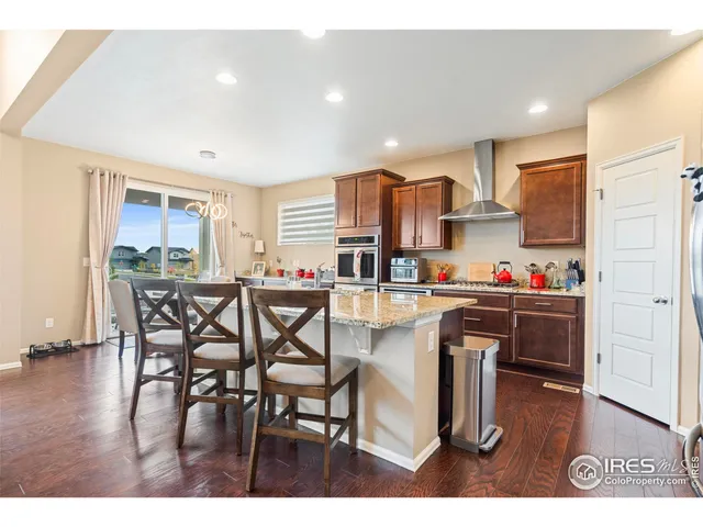 a kitchen with stainless steel appliances a refrigerator a stove a sink dishwasher and a dining table with wooden floor