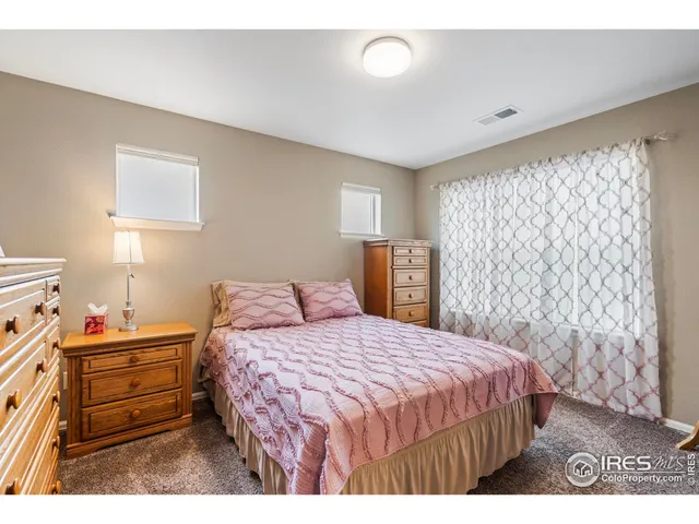 a bedroom with a bed a mirror on dresser and a chandelier