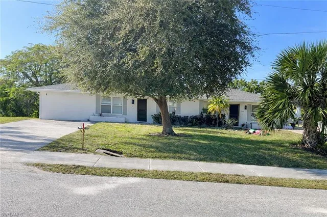 a view of a house with a yard and large tree