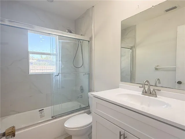 a bathroom with a granite countertop sink a toilet and shower