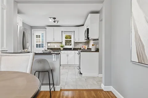 a kitchen with kitchen island granite countertop a sink cabinets and wooden floor