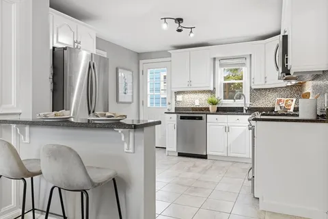 a kitchen with appliances cabinets and chair