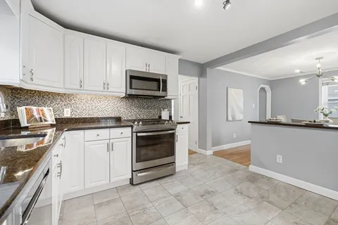 a kitchen with granite countertop a stove top oven microwave and cabinets
