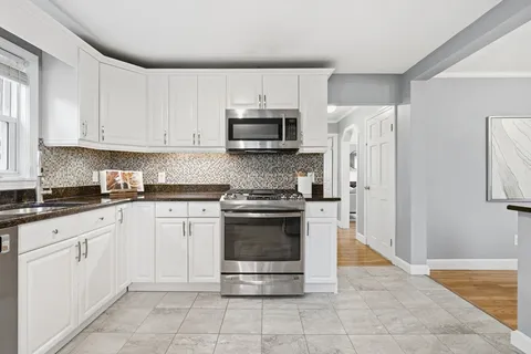 a kitchen with granite countertop white cabinets and stainless steel appliances