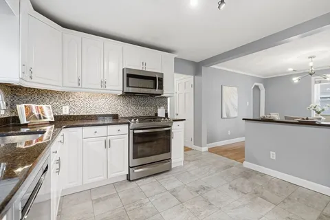 a kitchen with granite countertop a stove top oven microwave and cabinets