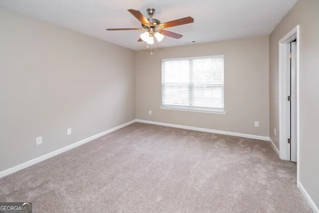 an empty room with a window and a ceiling fan