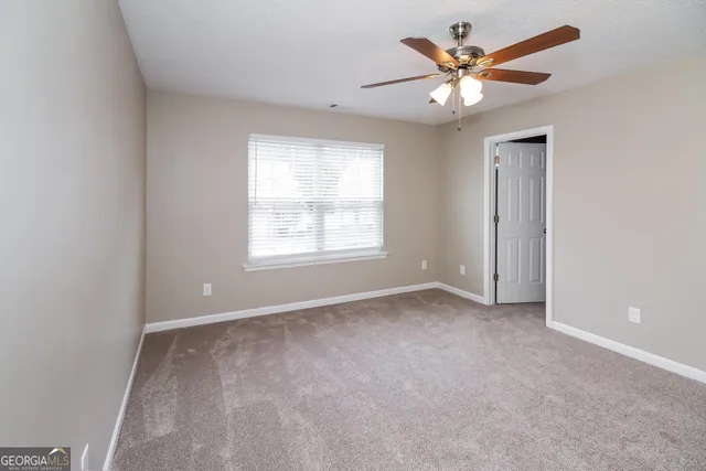 an empty room with a window and a fan