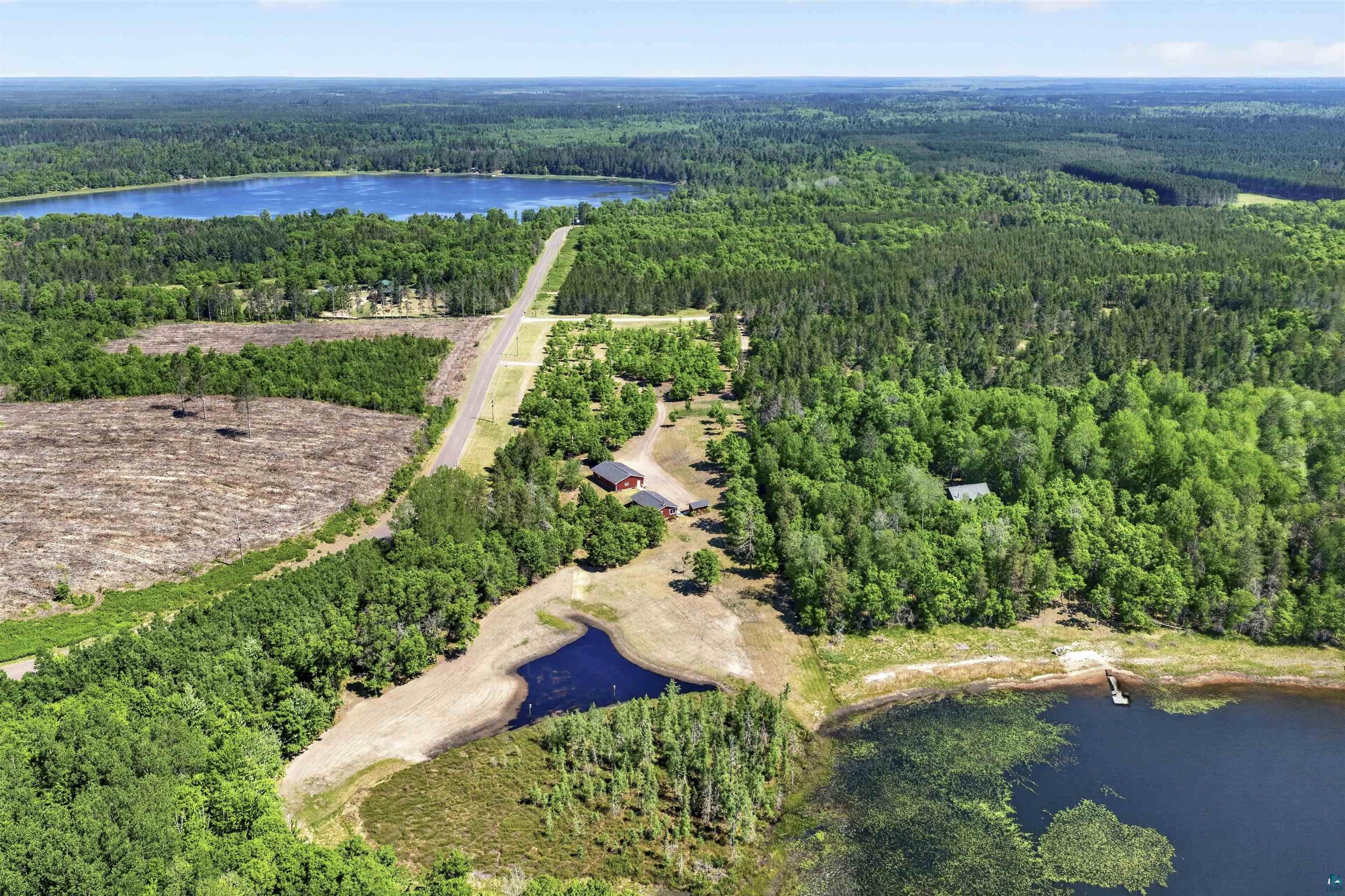 11702 East Mail Road Gordon, WI 54838 - Photo 10 of 60 Aerial perspective showcasing extensive wooded acreage, two substantial lakes, a private pond, and a long driveway leading to residential structures