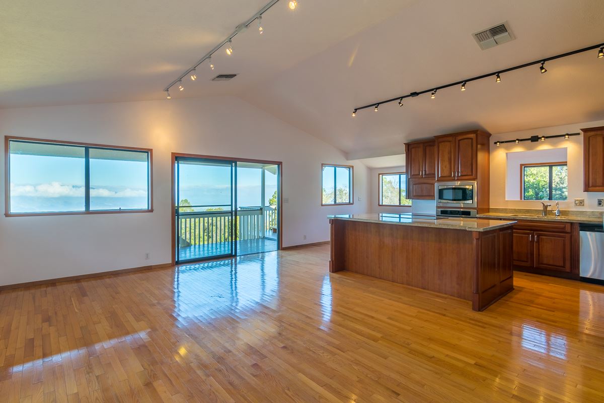 395 Middle Road Kula, HI 96790 - Photo 4 of 30 a kitchen with stainless steel appliances granite countertop a stove top oven a sink dishwasher a refrigerator and a dining table with wooden floor