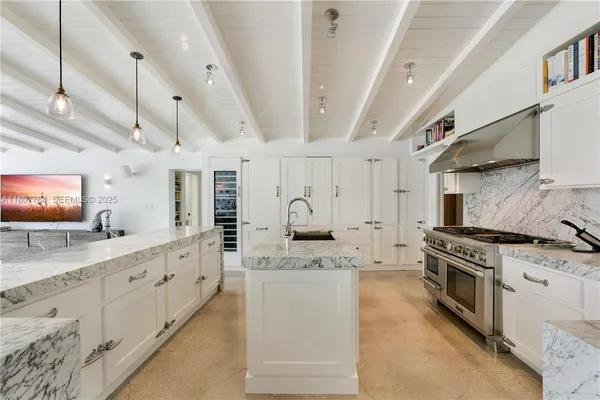 a large white kitchen with stainless steel appliances granite countertop a stove and a sink