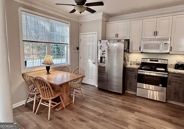 a kitchen with stainless steel appliances a dining table chairs refrigerator and cabinets